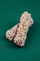 Sweet chocolate bars coated with corn cereals and peanuts pieces on green background.