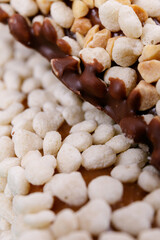 Macro shot of sweet chocolate bars coated with corn cereals and peanuts pieces.