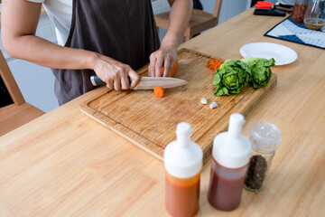 Woman cutting vegetables for cooking meal.