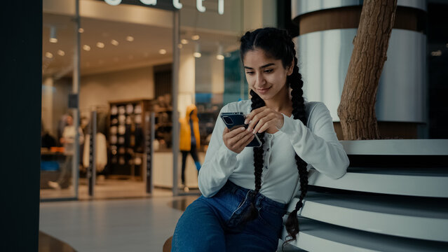 Female student middle-eastern girl businesswoman arabian ethnic woman student shopper chatting on phone sit at shopping center use mobile apps purchasing online read digital news watch internet video