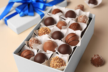 Box with delicious chocolate candies on beige background, closeup