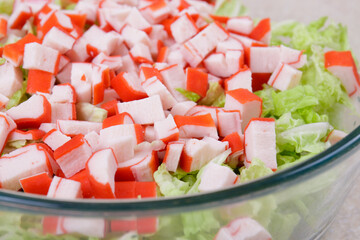 Fresh salad with crab sticks, lettuce and napa cabbage close up in glass bowl . Macro shot.