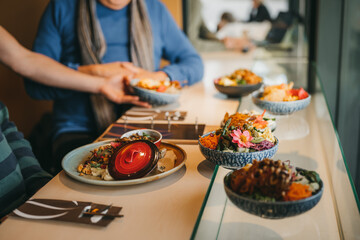Perspective shot of a table full of culinary food with waiter bringing a bowl to table