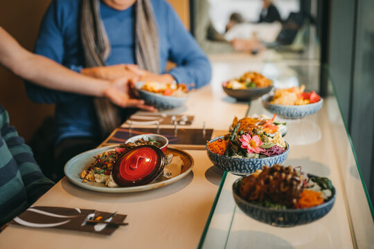 Perspective shot of a table full of culinary food with waiter bringing a bowl to table