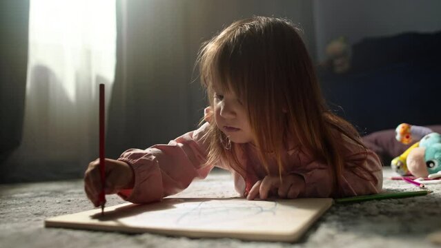 Happy childhood close-up of a girl drawing with pencils on a blackboard. The child paints a picture with different colors. High quality 4k footage