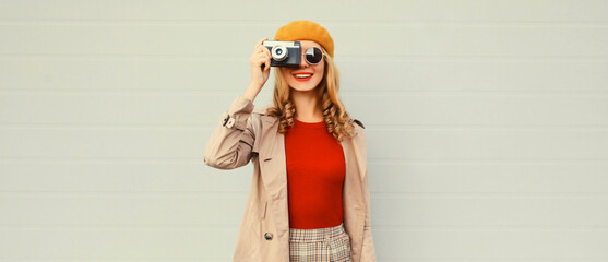 Fashionable autumn color style outfit, stylish young woman photographer with film camera wearing...