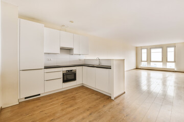 an empty kitchen with white cabinets and black counter tops in a room that has wood flooring on the walls