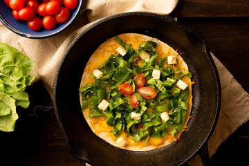 Cheesy Arugula Pizza with Cherry Tomatoes in Cast Iron Skillet in cropped front view