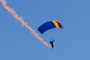 Skydivers descend gracefully from the vast expanse of the sky, their parachutes unfurling like giant blossoms in slow motion. As they approach the earth, a sense of exhilaration, triumph fills the air