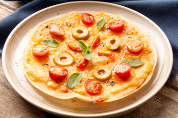 Pizza with tomatoes, olives, basil and cheese in a handmade ceramic plate in top view