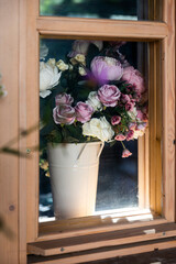 rustic bouquet of dried purple roses in a wooden window in the country