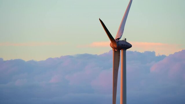 Wind turbine in the sky with clouds moving in background