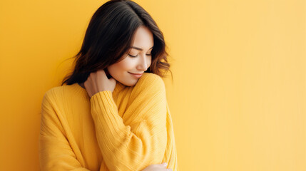 Female embracing herself on yellow background with copy space. - obrazy, fototapety, plakaty