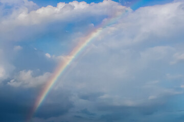 Fototapeta na wymiar Beautiful rainbow in the blue sky, white clouds