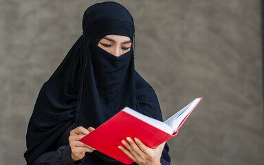 Portrait with copy space adult beautiful Muslim woman wearing black headscarf, traditional dress, reading, holding scripture book for praying with hope. Diversity, Religious Concept.