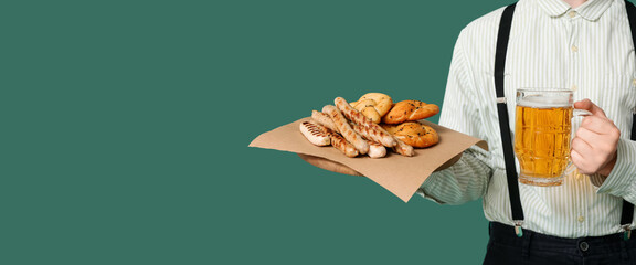 German man with beer and snacks on green background with space for text. Banner for Octoberfest