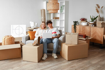 Young couple using laptop in room on moving day