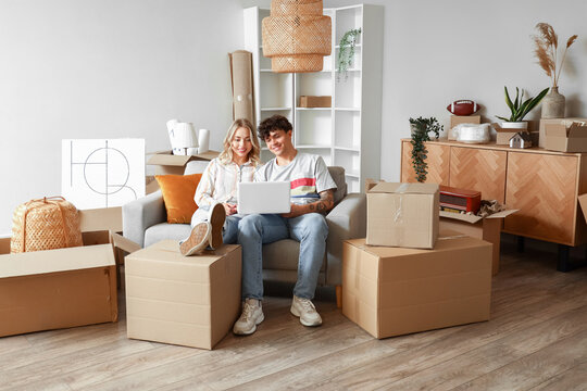 Young couple using laptop in room on moving day