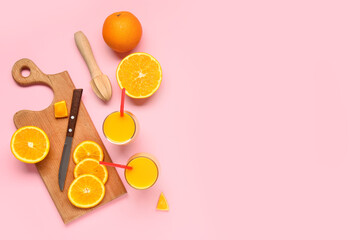 Glasses of fresh orange juice and wooden juicer on pink background