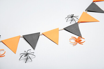 Garland made of paper flags and spiders for Halloween celebration on white background, closeup