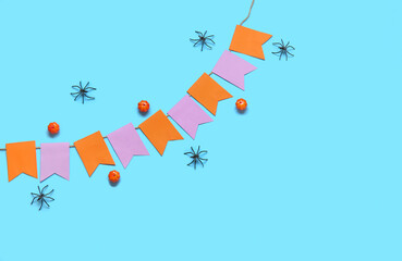 Garland made of paper flags, pumpkins and spiders for Halloween celebration on blue background
