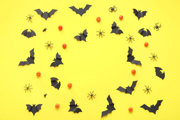 Fototapeta na wymiar Frame made of pumpkins, paper bats and spiders on yellow background. Halloween celebration concept