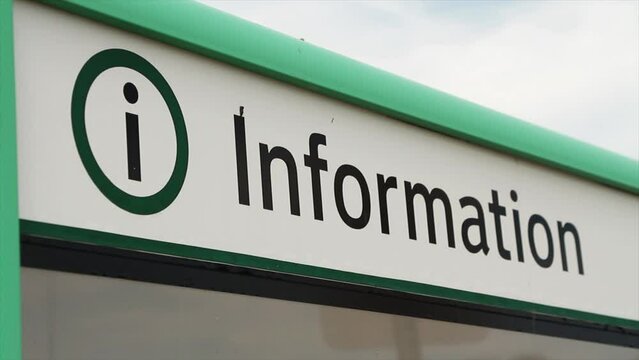 close on the caption information in black writing on a white background, green border on top, letter i in a circle next to it, with an empty glass bulletin board beneath it, shot on angle