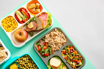 Lunchboxes with different delicious food on color background