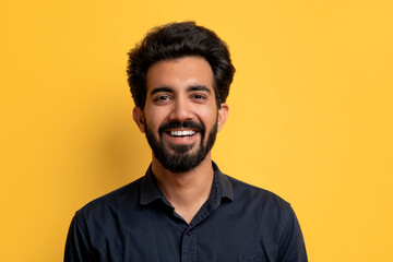 Portrait of handsome smiling indian man posing on yellow studio background