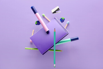 Different flying stationery on lilac background