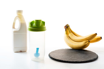 Products for sports nutrition. Empty sports shaker and bananas with milk on the table. Products on...