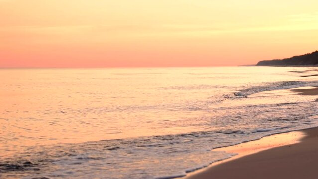 Beautiful sea coast with reflection of orange sunrise light. Gold and yellow colors sky, clouds. Calm waves scene, sunny day, beach, shore, outdoor, static shot, mid shot, real time, hd. ProRes 422 HQ