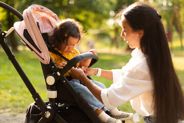 Caring Korean Mom Ensuring Infant Daughter's Safety In Stroller Outdoor