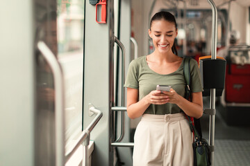 Joyful Passenger Woman Texting On Mobile Phone In Modern Tram - obrazy, fototapety, plakaty