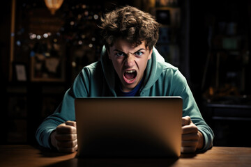 Young teenage boy plays computer games on laptop computer. The player is upset about the defeat. Crazy angry frustrated game addict teenager lost his computer game