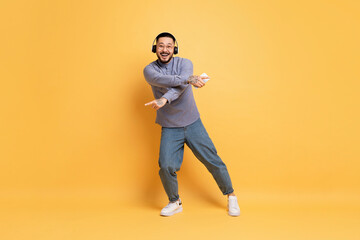 Fototapeta na wymiar Full Length Shot Of Cheerful Young Asian Man Dancing On Yellow Background