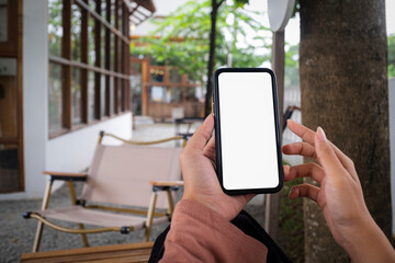 Close-up of hand holding a blank white smartphone screen. Blurred background. Mockup..