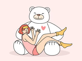 Giant teddy bear near sitting teenage girl in pajamas and sleep mask. Funny schoolgirl teen age looks at screen lying on feet of toy bear rejoicing at cute gift from parents or boyfriend - obrazy, fototapety, plakaty