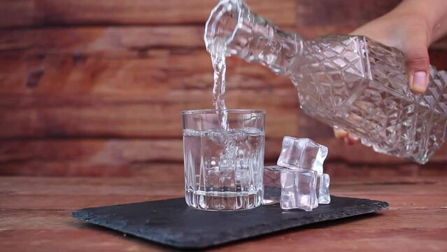bartender pouring clear liquor such as vodka or tequila from fancy bottle