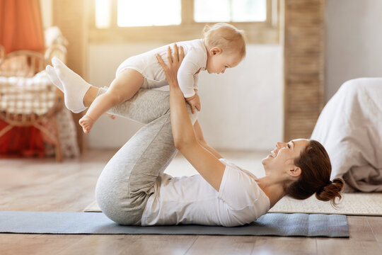 Young mother workout together with her baby toddler at home