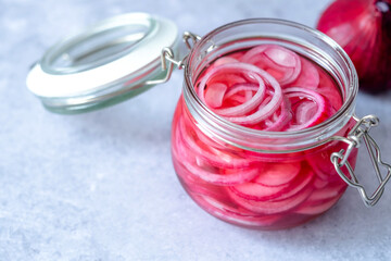 Pickled red onion rings on a wooden spoon on a glass jar. Appetizer, condiment or topping. Healthy...