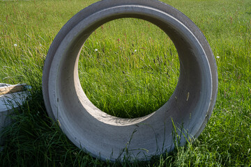 A concrete manhole in a grass field.