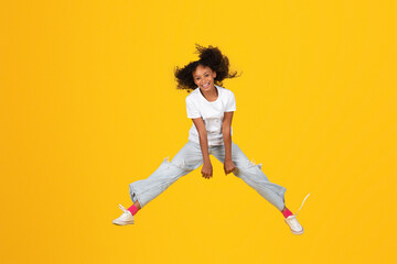 Fototapeta na wymiar Happy excited adolescent african american girl in white t-shirt jump, freezes in air, has fun