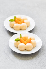 Apricot cream dessert, Panna Cotta in the shape of truffles, decorated with fresh apricot slices. On a plate. LIght grey background. Close up
