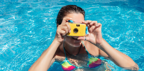 Unrecognizable young woman using vintage camera in swimming pool