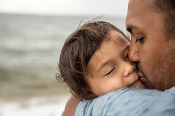 Closeup portrait of father kissing his little daughter, happy family and parenthood concept