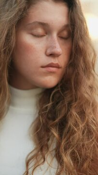 A detailed shot of the pretty girl's face, showcasing freckles and curly hair.