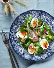 beef tongue lunch with eggs and vegetables on a vintage plate on a table with blue tablecloth