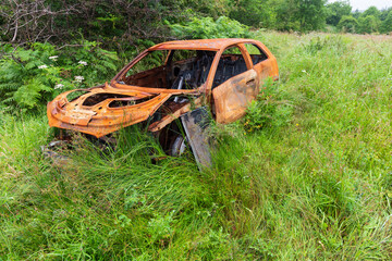 A wreck of a old burnt out car abandoned in the countryside  