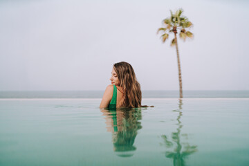 Obraz na płótnie Canvas Chica delgada con pelo largo posando en una piscina de un hotel paradisiaco 